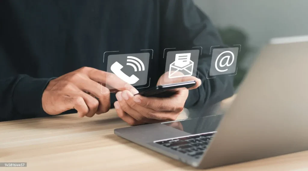 Persona che usa uno smartphone accanto a un computer portatile